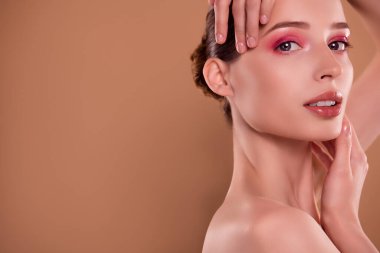 Çekici kadın dokunuşunun fotoğrafı, kahverengi boş alan üzerinde güzellik salonu ürününü tanıtan parlak makyaj malzemelerini gösteriyor..