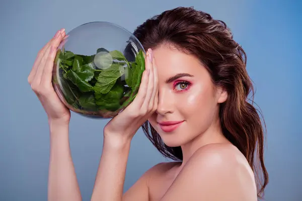 女子用玻璃球遮掩半脸有机绿色植物分离灰色背景的照片 — 图库照片