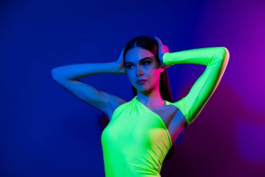 Güzel model kız ellerinin portresi saçlara dokunuyor. Parlak neon arka planda izole edilmiş boş bir alan reklamı gibi görünüyor..
