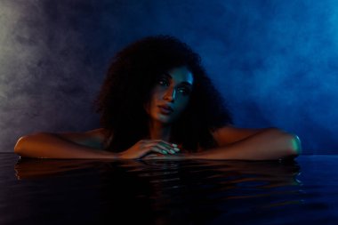 Çıplak, suya dokunan bir kadının hafta sonunu kaplıcada mavi ultraviyole banyoda dinlenerek geçirdiği fotoğraf..