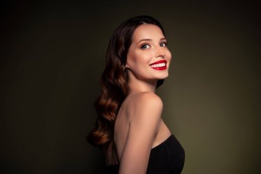 Profil tarafı fotoğrafı. Mutlu, mükemmel, zarif bir bayan. Siyah bir elbise giyip kutlama gecesi kutlamaları yapıyor..