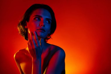 Güzel, rüya gibi bir kadının fotoğrafı çıplak omuzlar kollar yanak boş alan izole kırmızı neon arkaplan.