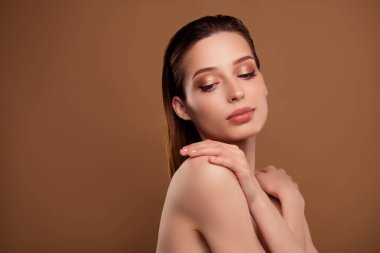 Güzel, parlak, çıplak bir kadının, kendine sarıldığı, izole edilmiş bir bej arka plan fotoğrafı..