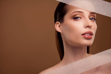 Kinesio bantları kullanarak parlak, güzel bir kadının çıplak bir fotoğrafı. Boş boş alan izole edilmiş bej arka plan..