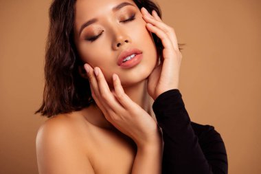Omzundan sarkan güzel, parlak kadının fotoğrafı. Cilt bakımının keyfini çıkar. Boş alan, izole edilmiş kahverengi arka plan..