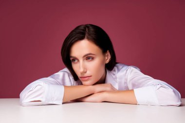 Beyaz masa elleri uzanmış bir kızın fotoğrafı. Profil tarafına bak. Gözden uzak pembe bir arka plan düşün..