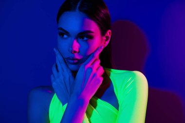 Kırpılmış güzel model kız ellerinin yüzlerine dokunurken çekilmiş fotoğrafı neon arka planda izole edilmiş boş bir alana benziyor..