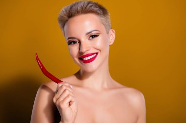 Parlak makyajlı mutlu bir kadının fotoğrafı kırmızı biberi pastel kahverengi arka planda izole eder..