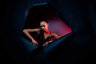 Latince kız fotoğrafı yırtık kağıda dokunarak izole edilmiş koyu mavi arkaplandan çıkıyor..