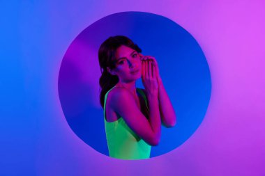 Kız ellerinin daire deliğinden dokunduğu fotoğraf. Kağıt afiş izole edilmiş pembe neon arkaplan..