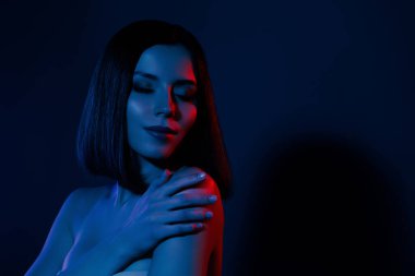 Kızın fotoğrafı, omuzları kapalı, gözleri kapalı, hassas, izole, neon rengi arka plan..