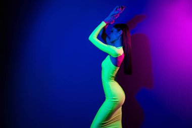 Kendine güvenen seksi model kızın profil portresi ellerinizi kaldırın boş görünüyor neon arka planda izole edilmiş poz verin.