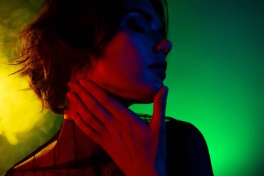 Kadının profil fotoğrafı yana bak. Boynuna nazik bir şekilde dokun. Gözlerin kapalı, renk arkaplanı izole..