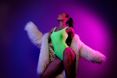 Mor renkli neon arka planda izole edilmiş, tutkulu, şık model kız dans partisinin portresi..