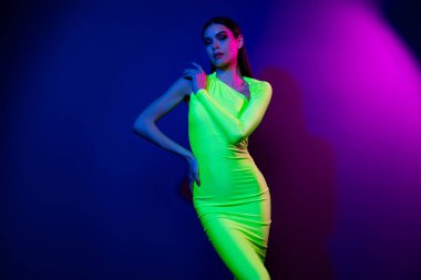 Oldukça narin, kendine güvenen bir kızın portresi, parlak neon arka planda izole edilmiş omuza dokunuyor..