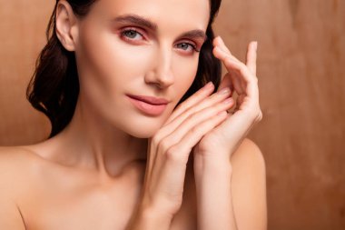 Esmer bukleli bir kadının yakın plan fotoğrafı. Ellerine dokun. Yumuşak ten, izole ahşap arka planın tadını çıkar..