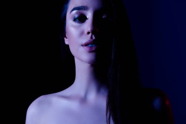 Çekici, dumanlı gözlü bir kızın fotoğrafı. Ayırt edici, karanlık, neon renkli bir arka plan..