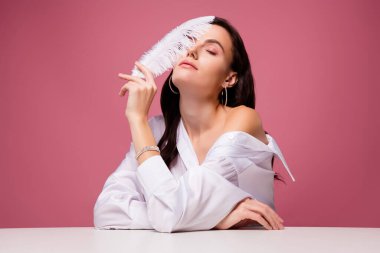 Kızın fotoğrafı. Masa başında, gözleri kapalı. Yumuşak dokunuşlu yüz, izole edilmiş pastel arka plan..