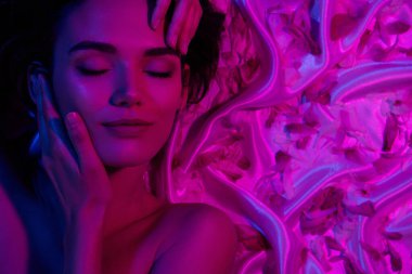 Genç bayan memnuniyetinin portresi. Yüz tazeliği prosedürü. Gözlerinizi kapatın ve neon ışıklı arka planda rahatlayın..