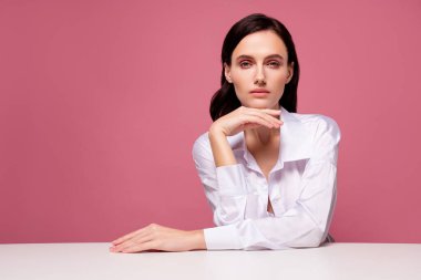 Oturma masasında oturan kızın fotoğrafı zarif bir dokunmatik el çene izole pembe arka plan hisset.