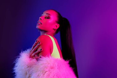 Kürk giyen, kendine ait menekşe rengi arka planı olan çekici bir kadının fotoğrafı..