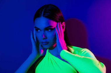 Göz kamaştırıcı şık model kız ellerinin fotoğrafı. Yüze dokunmak. Mor renkli, neon ışıklı arka planda izole edilmiş boş bir yere benziyor..