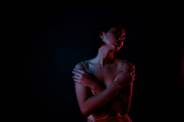 Seksi giyinmiş, parlak, çekici bir kadının fotoğrafı. Kendini boş, izole, siyah bir arkaplan gibi kucakla..