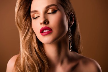 Kapalı gözleri olan, bej rengi arka planda izole edilmiş, güzel, genç bir kızın yakın plan fotoğrafı..