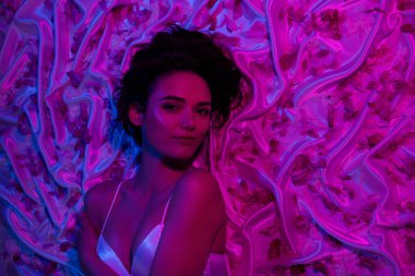 Baştan çıkarıcı kız arkadaşın en iyi görüntüsü romantik yatak odasındaki neon ışıklı çarşaflarda erkek arkadaşını bekle..