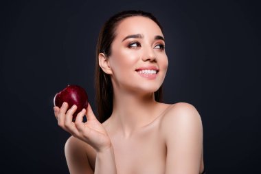 Mutlu, gülümseyen bir kızın fotoğrafı. Profil profiline bak. Elma izole edilmiş koyu renk arka plan..