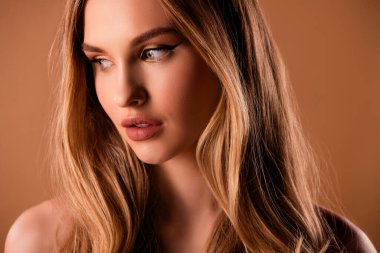 Güzel, genç bir kızın yakın plan fotoğrafı. Bej renkli arka planda izole edilmiş hiçbir kıyafet yok..