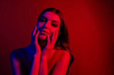 Göz kamaştırıcı genç bayan portresi. Yüzü boş, çıplak omuzları neon mavisi arka planda izole edilmiş..