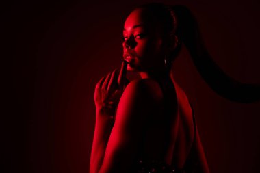 Afrikalı bir kadının fotoğrafı. Bak, dokun, dokun, dudaklara dokun, flört et, izole edilmiş kırmızı renk, neon arka plan..