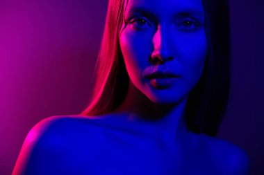 Çekici ve güzel bir kızın fotoğrafı cezbedici görünüyor. Neon ultraviyole renkli arka plan altında soyutlanmış görünüyor..