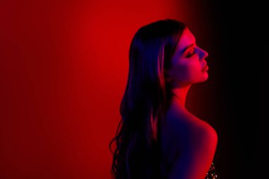 Göz kamaştırıcı genç bayanın profil fotoğrafı boş uzay giysisi kırmızı mavi neon arka planda izole edilmiş.