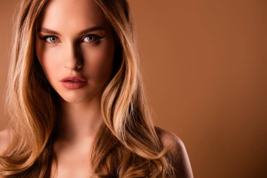 Güzel, genç bir kızın boş bir alanda çekilmiş fotoğrafı. Bej renkli arka planda izole edilmiş kıyafet yok..