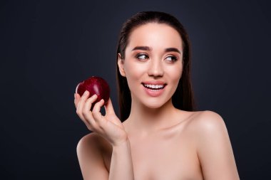 Elma meyvesi tutan çekici bir kadının fotoğrafı. Profil profiline bak. Koyu renkli arka plan..