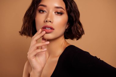 Hayalperest, baştan çıkarıcı kadının fotoğrafı. Omuzları aşınmış siyah beden giysisi. Parmak izi, izole edilmiş bej arkaplan..