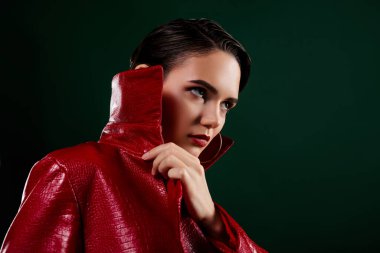 Kırmızı ceketli, yakın yüzlü bir kızın fotoğrafı boş görünüyor izole edilmiş koyu yeşil arkaplan.