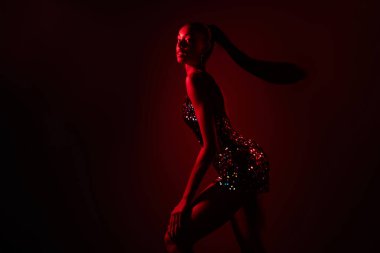 Afrikalı bir kadının hareket halindeki fotoğrafı kırmızı neon arkaplan üzerinde izole edilmiş bir poz..