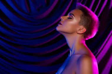 Çıplak bir kadının, kendini kabullenme zevkini çıkarırken çekilmiş bir fotoğrafı. Boş bir alan. Mor neon renkli keten..