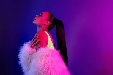 Çekici bir kadının kabarık ceketli, kendine sarılıp gece partisinin tadını çıkarırken çekilmiş fotoğrafı..