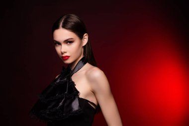 Kadının siyah gece elbisesi giydiği fotoğraf. Kameraya bak. Telif alanı, izole edilmiş kırmızı arka plan..
