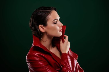 Profil tarafı fotoğrafı. Çekici bayan, kapalı gözler. Kırmızı cekete dokun..