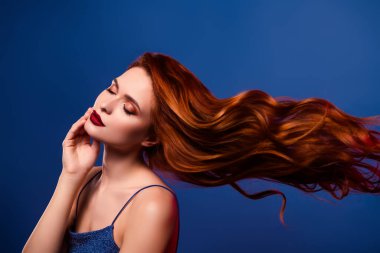 Rüya gibi narin, çarpıcı, hoş bir bayanın mavi arka planda izole edilmiş bakım prosedürünün zevkini çıkardığı fotoğraf..