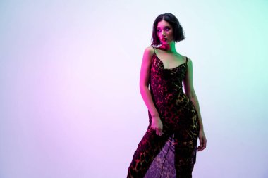 Baştan çıkarıcı kadının fotoğrafı. Elbise giy, empatiye özgü pozlar ver. Mavi arka plan..