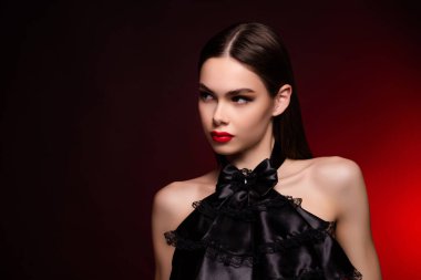 Siyah gece elbisesi giyen bir kadın. Boş görünüyor. Flört eden kırmızı bir arkaplan..