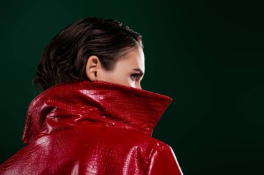 Gizemli kızın fotoğrafı geri çekil profil kenarına bak boş alan izole edilmiş yeşil arkaplan.