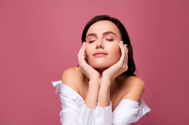 Esmer kadının fotoğrafı. Yüzüne dokunuyor. Parmakları kapalı..