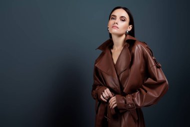 Moda yağmurluklu kendine güvenen çekici bayanın güzellik dergisi. Boş alan koyu gri arka planda izole edilmiş..